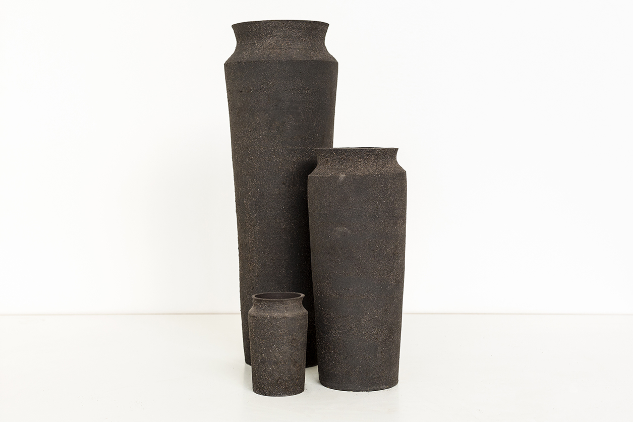 A cluster of three tapered vases with same shape, but different heights and each with top rims curved in and outwards.