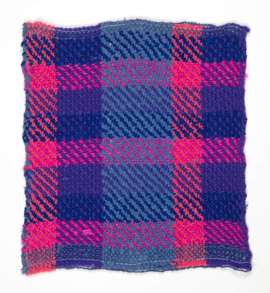 wovent textile sample of blue and magenta threads in a plaid pattern, mounted onto a white board