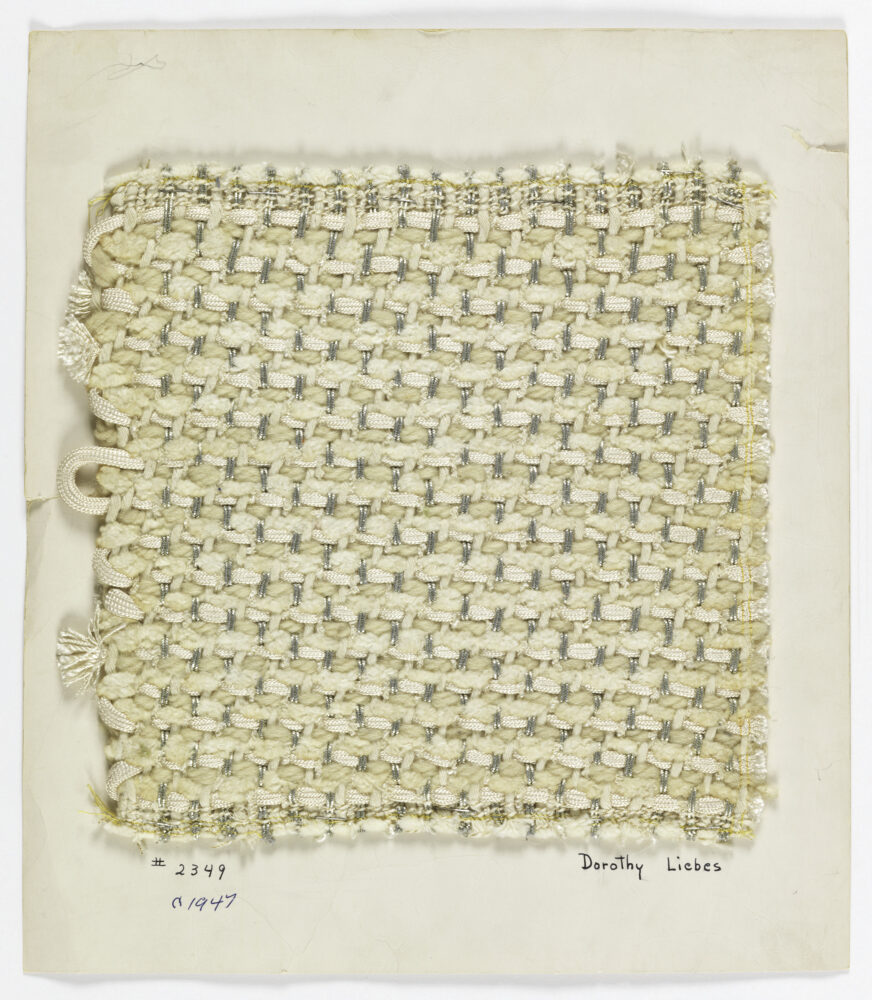 woven textile sample of cream and metallic threads mounted onto a white board
