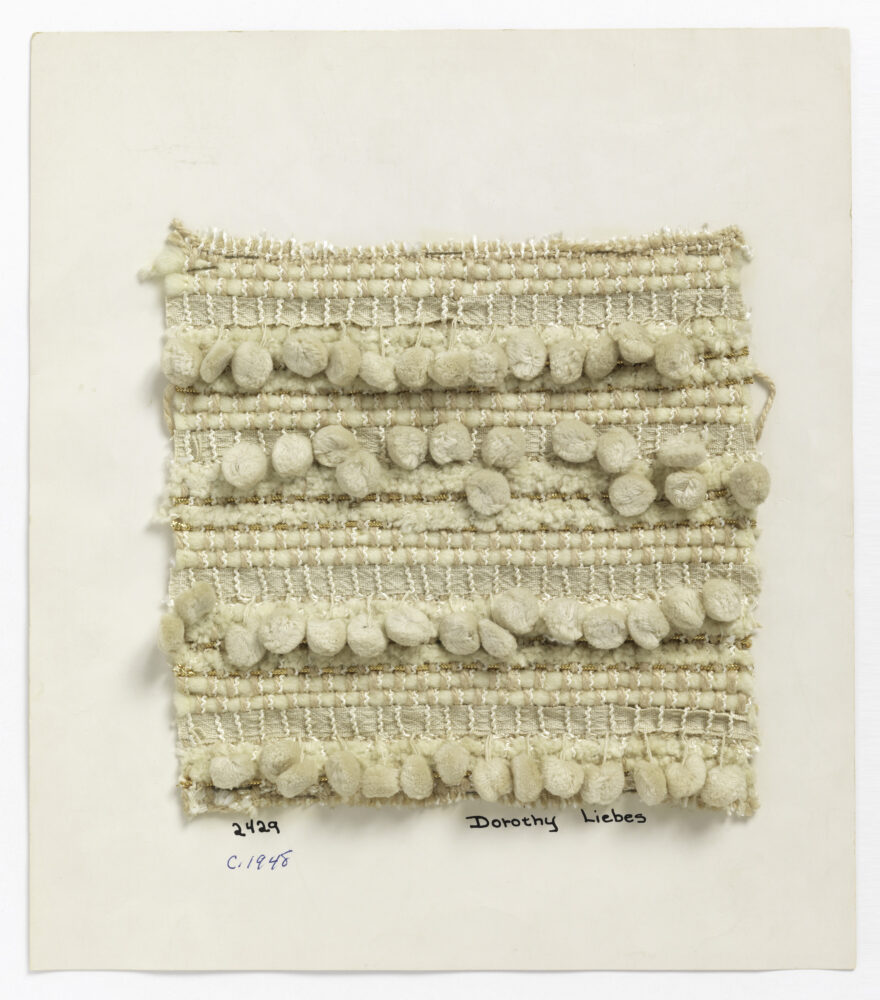 woven textile sample of cream thread with pom pom details