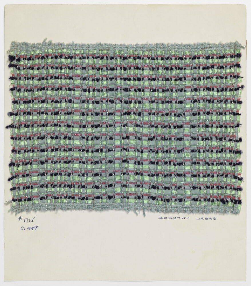 woven textile sample comprised of teal, magenta and black threads mounted on a white board