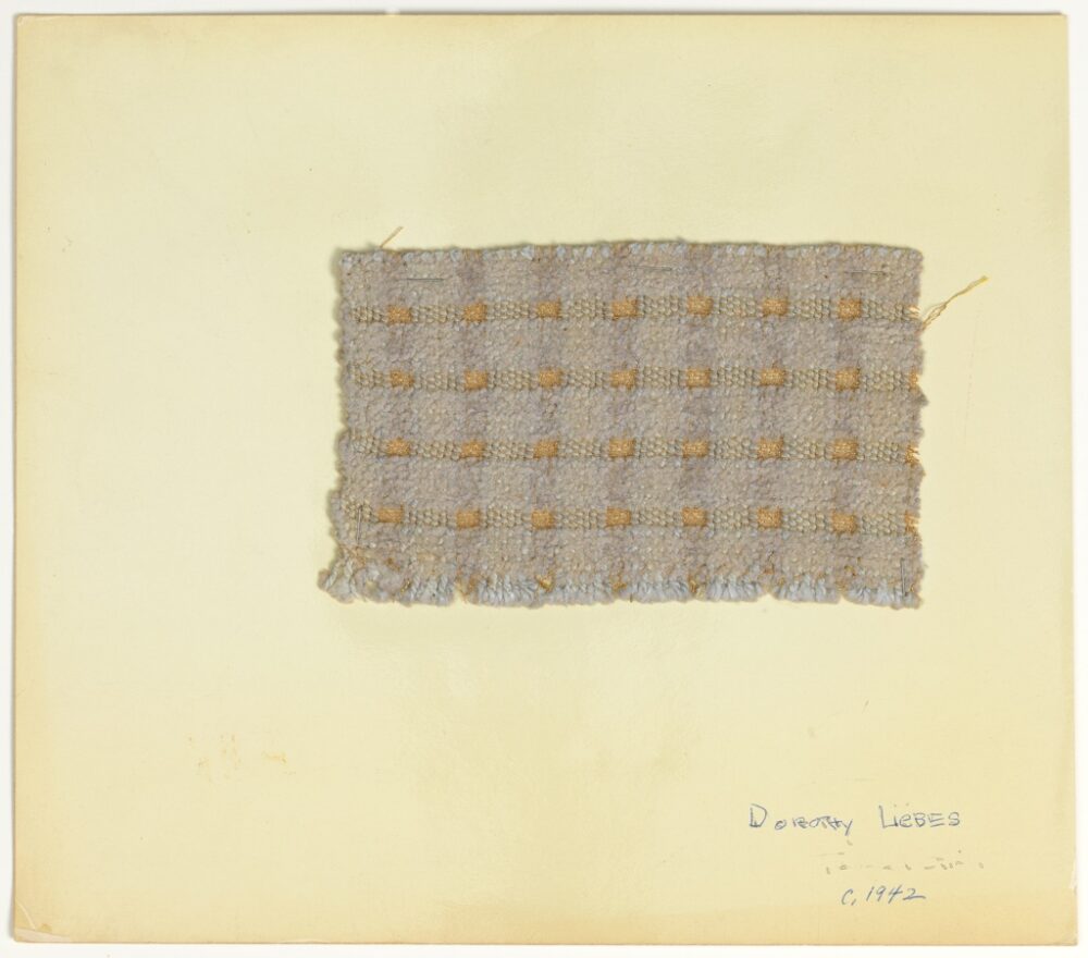 woven textile sample of greyish purple thread mounted onto a white board