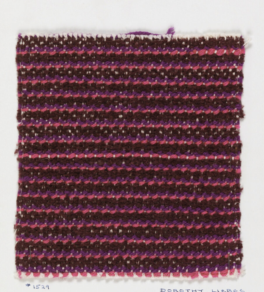 woven textile sample of magenta and navy threads mounted onto a white board