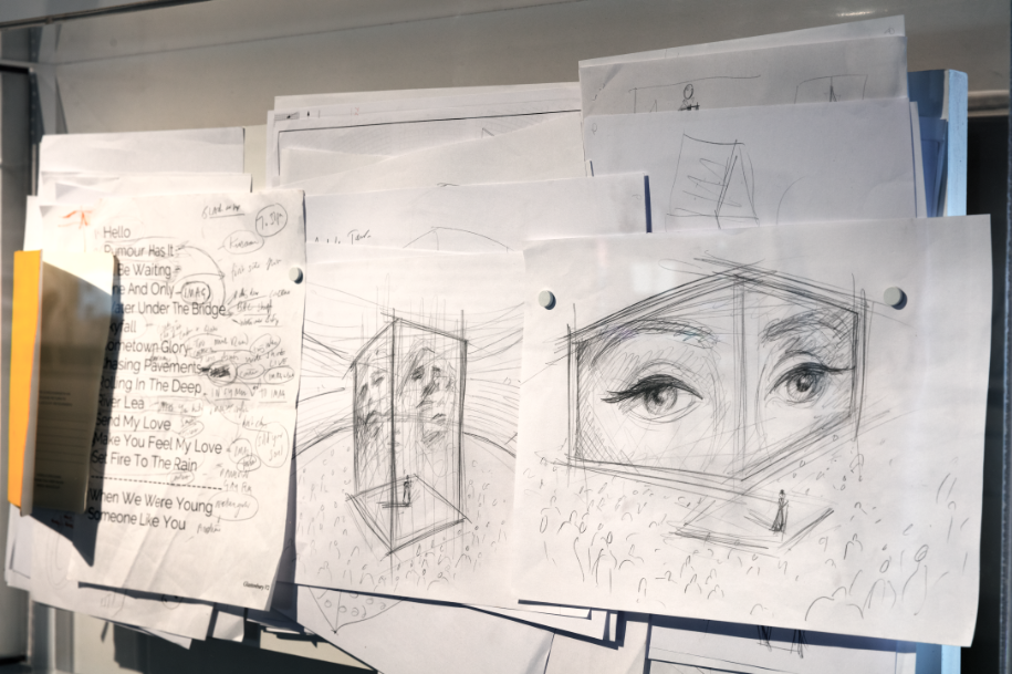 Collection of drawings pinned to a wall depicting rectangular prisms with eyes.