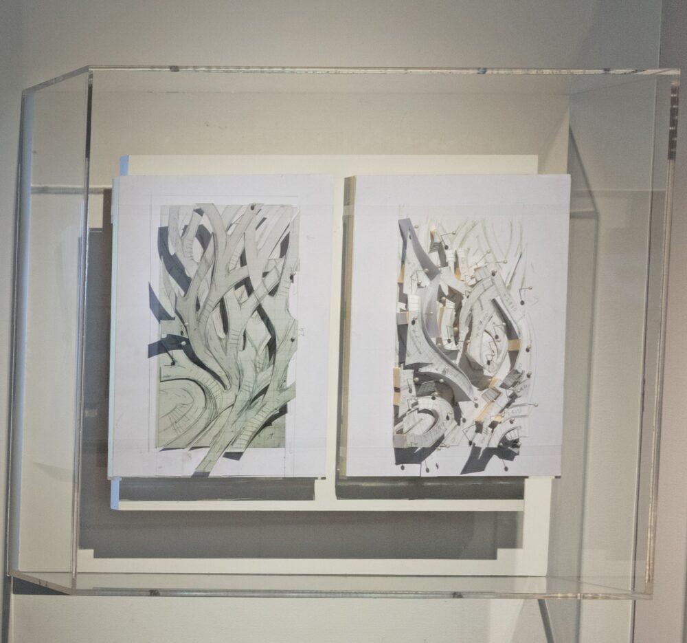 A clear case houses two white rectangular objects, each with three-dimensional, branch-like forms on them in pastel colors.