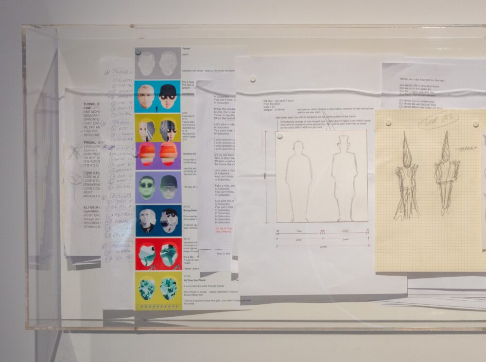 Collection of papers pinned to a wall with printed text and drawings of people.