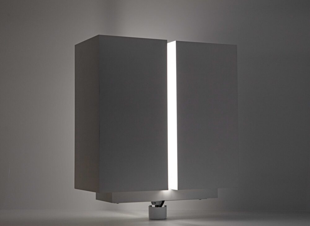 White cubic model that is split in half, vertically, and slightly parted; light glows from within the model.