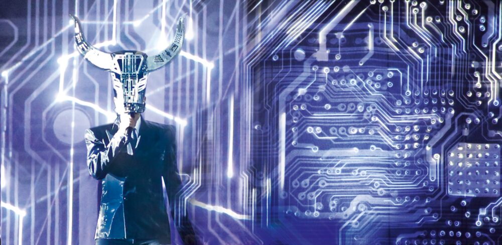 Person in a suit holding a mask with horns in front of their face with a dynamic background of purple, blue, and white electric circuitry.