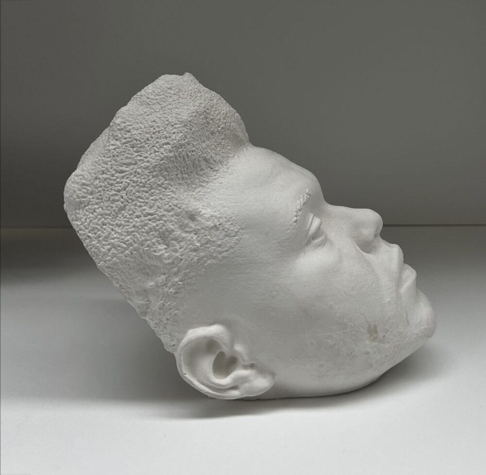 A model of musician Abel “The Weeknd” Tesfaye’s head made in a white material faces right and sits on a white surface.