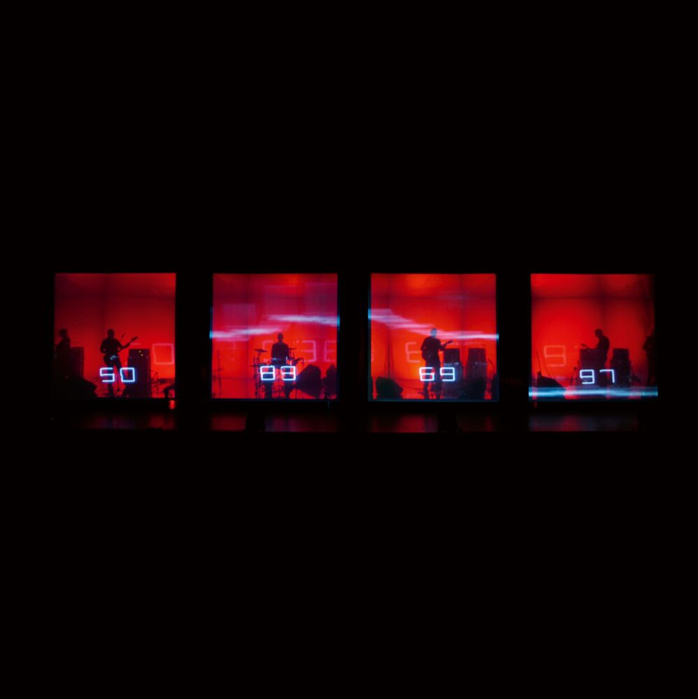 Row of four red translucent cubes, each with a black silhouette of a band number inside