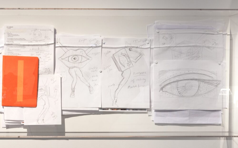 Several drawings pinned to a wall depicting legs, eyes, and a mouth.