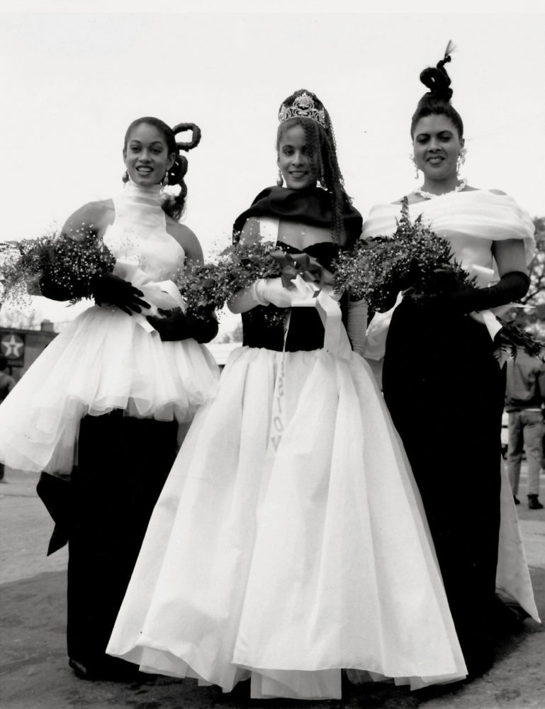 Grayscale image of three African American actresses in homecoming court gowns on set of School Daze film