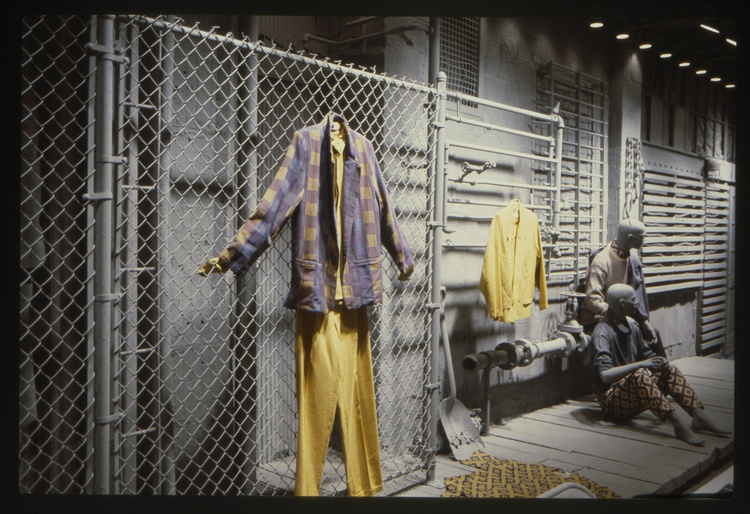 Image of brightly colored, patterned yellow and blue WilliWear garments displayed in WilliWear New York showroom on mannequins, along wall, and on the floor