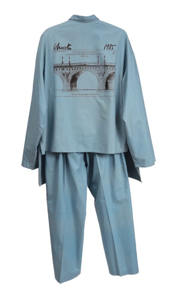 Light blue cotton ensemble consisting of a long sleeve shirt and pants. The ensemble is photographed from the back and a screenprint drawing of a bridge with text stating [Christo / 1985] is displayed on the shirt.